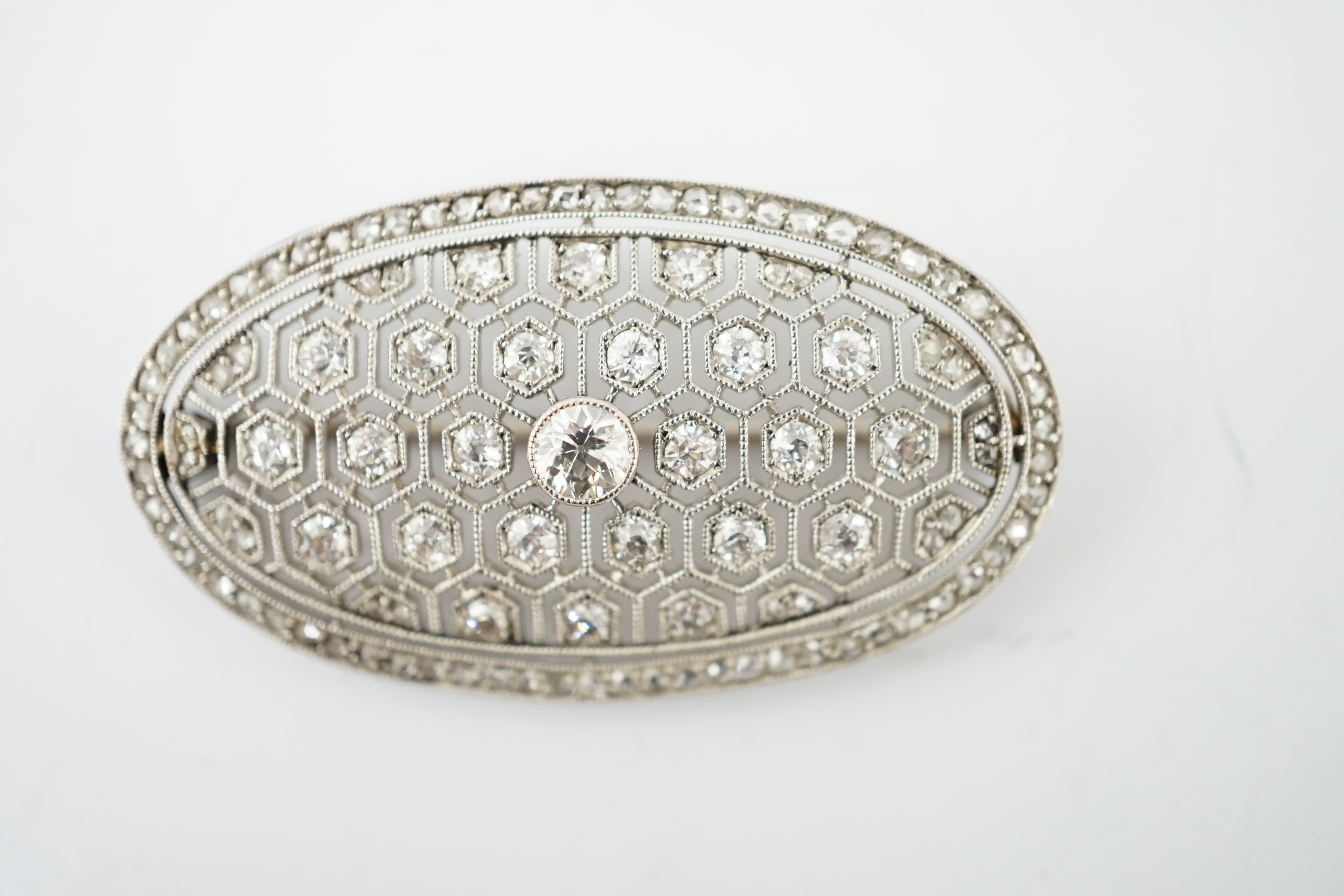 A Belle Epoque platinum and millegrain diamond cluster set oval brooch